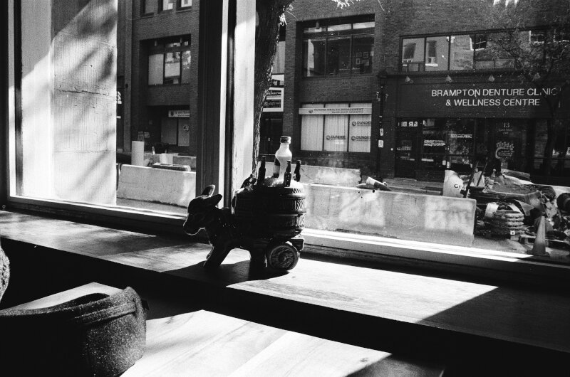 A window with a figurine of a little donkey pulling a cart full of bottles.