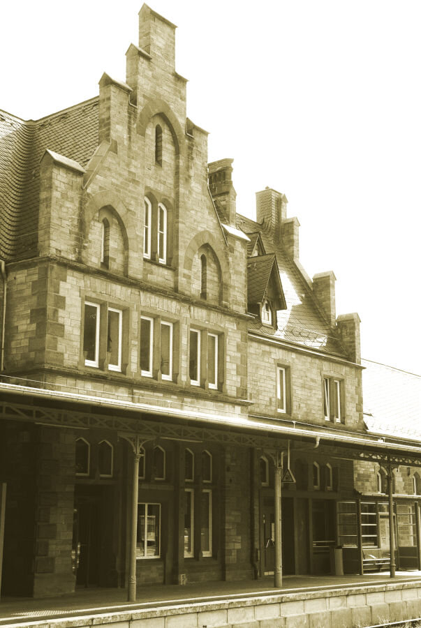 A stone railway terminal with tall roofs and narrow pointed windows.