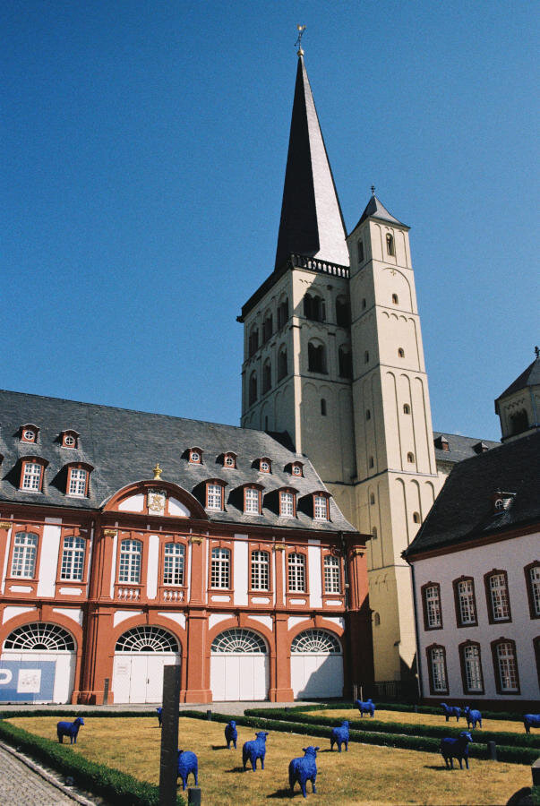 A cloister garden with a red And white building connected to a tan stone church.