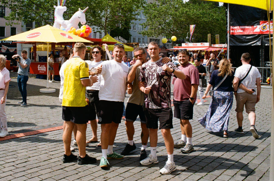 A group of men in black shorts and different color shirts pose and smile for the camera