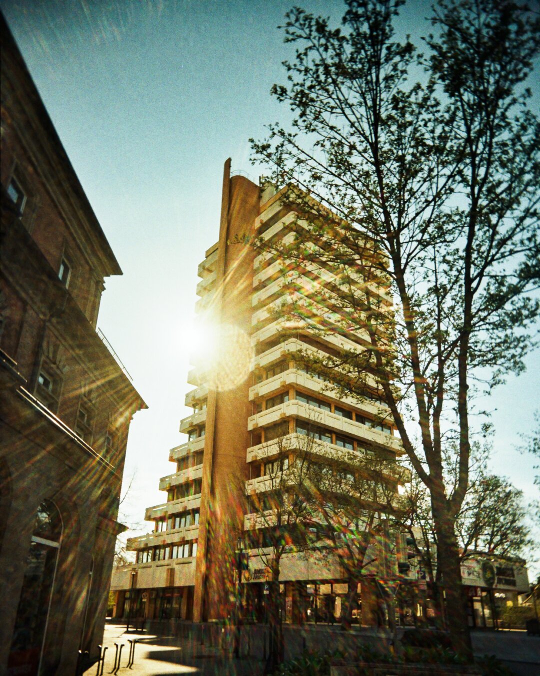 High-rise building with balconies in Crailsheim, sun shining behind a tree and a vertical structure in the foreground. *** Hochhaus mit Balkonen in Crailsheim, Sonne scheint hinter einem Baum und einem vertikalen Element im Vordergrund.