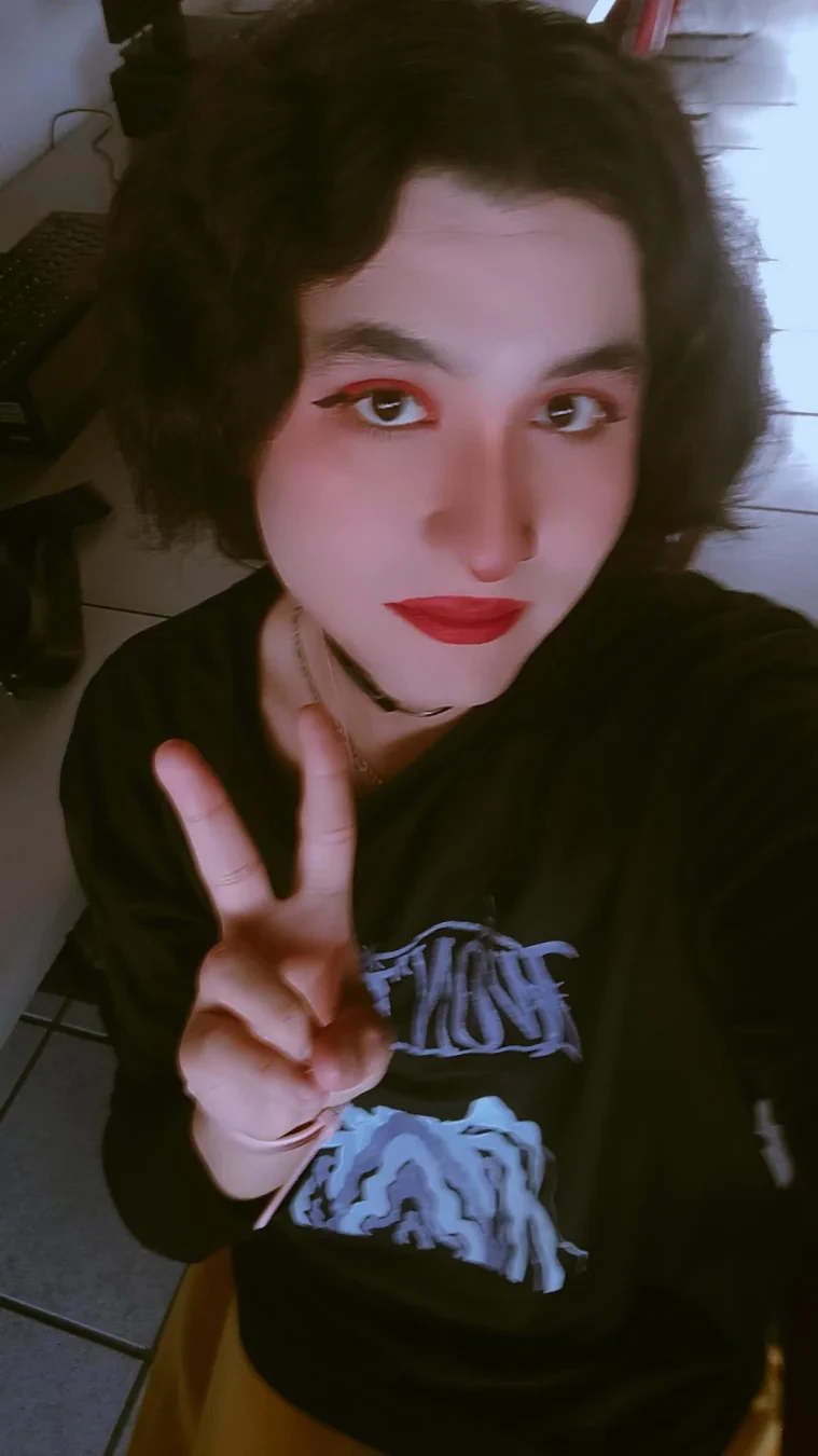 A selfie doing the peace sign and wearing a black T-shirt and a yellow skirt.