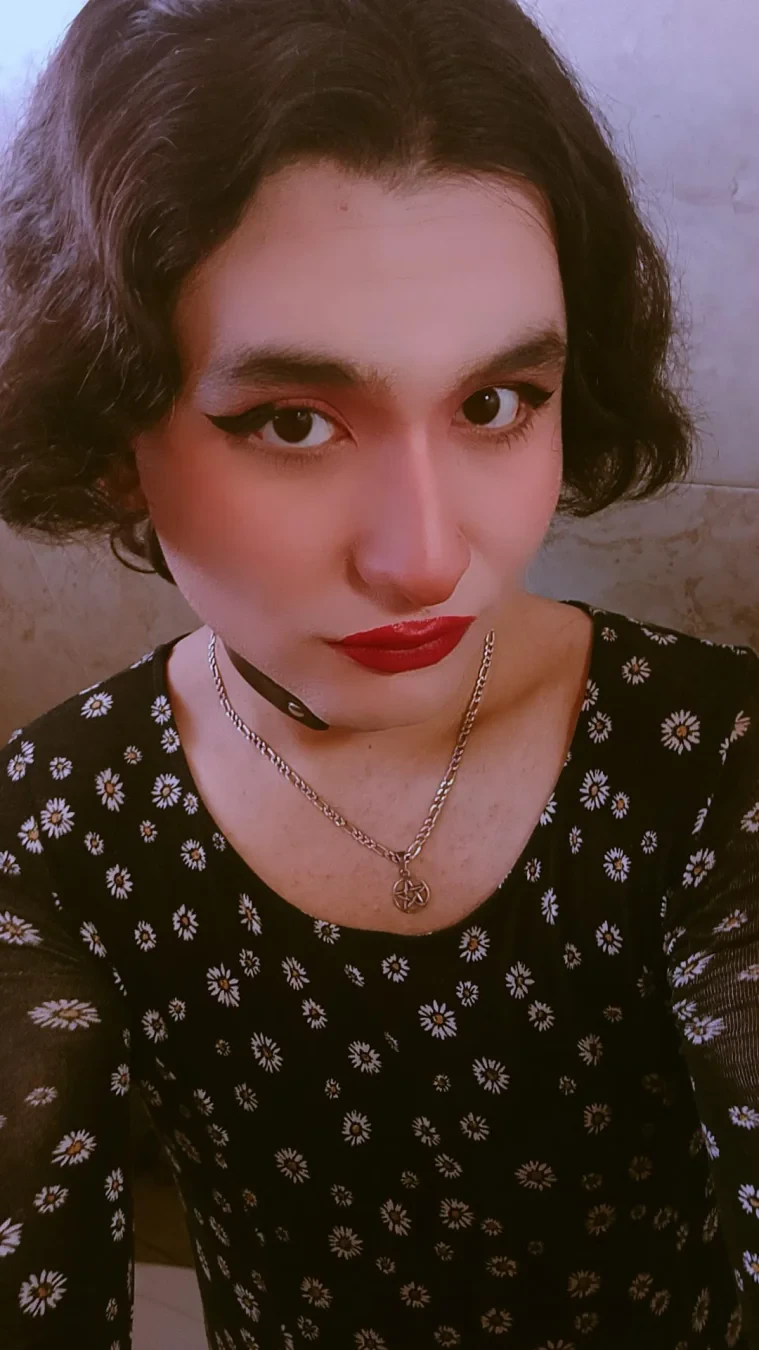 A selfie wearing a short dark flowery dress.