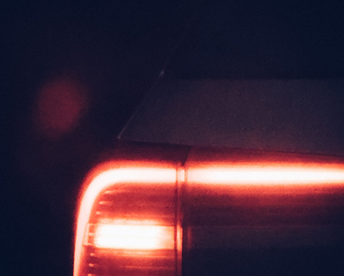Ein Rücklicht eines Autos leuchtet in der Dunkelheit.