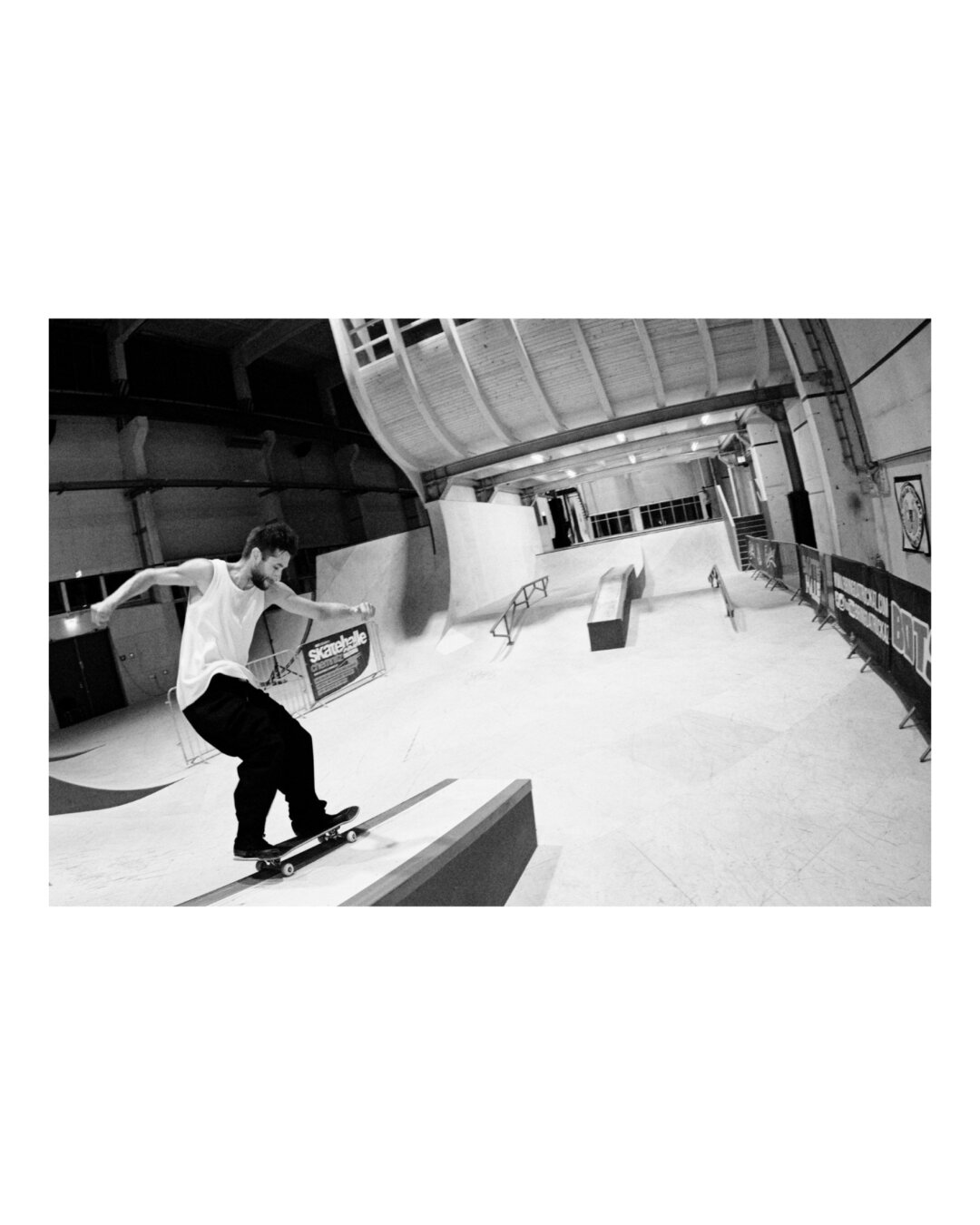 Skateboarding grinding trick, 50/50. Black and white, fisheye optic.