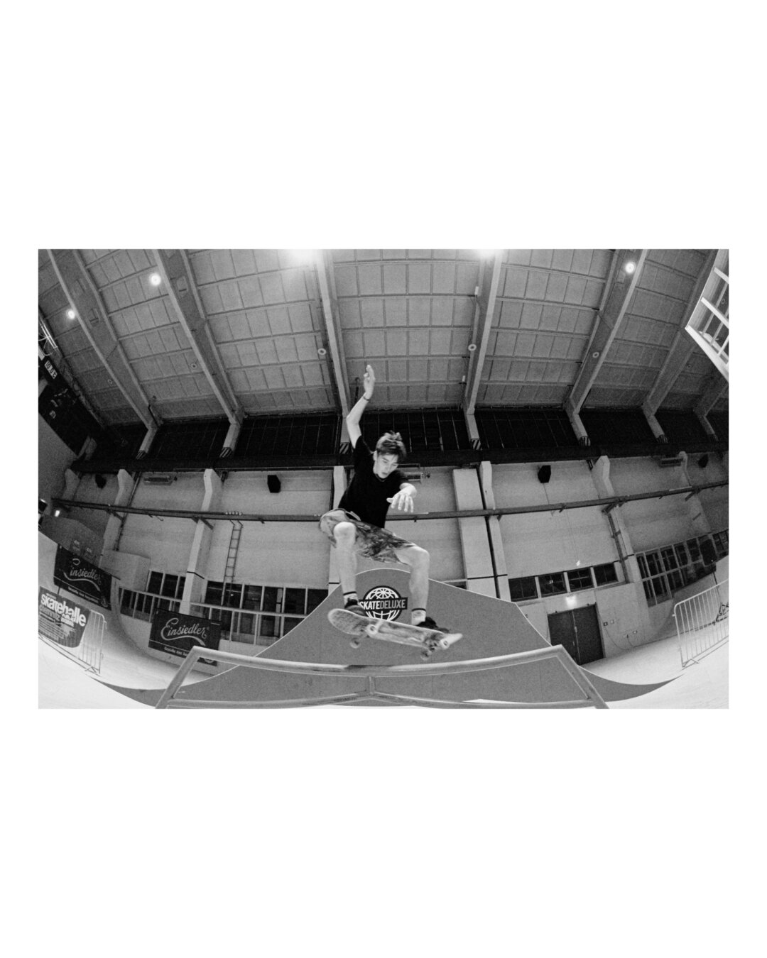 Skateboarding trick on a rail. Black and white, shot with a fisheye lens.