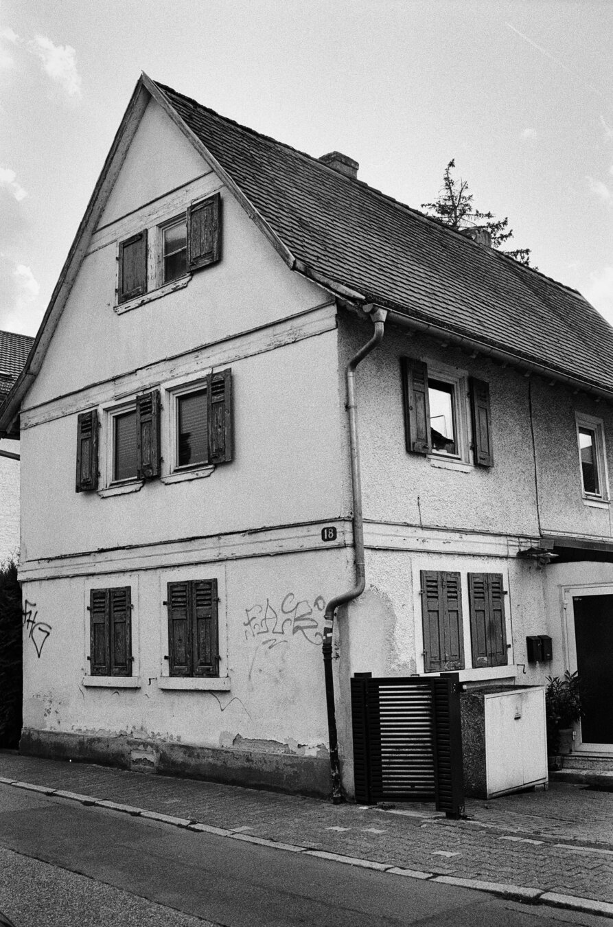 Analog color photo of an older white apartment house with three floors, build postwar period, located in Alt-Ginnheim.