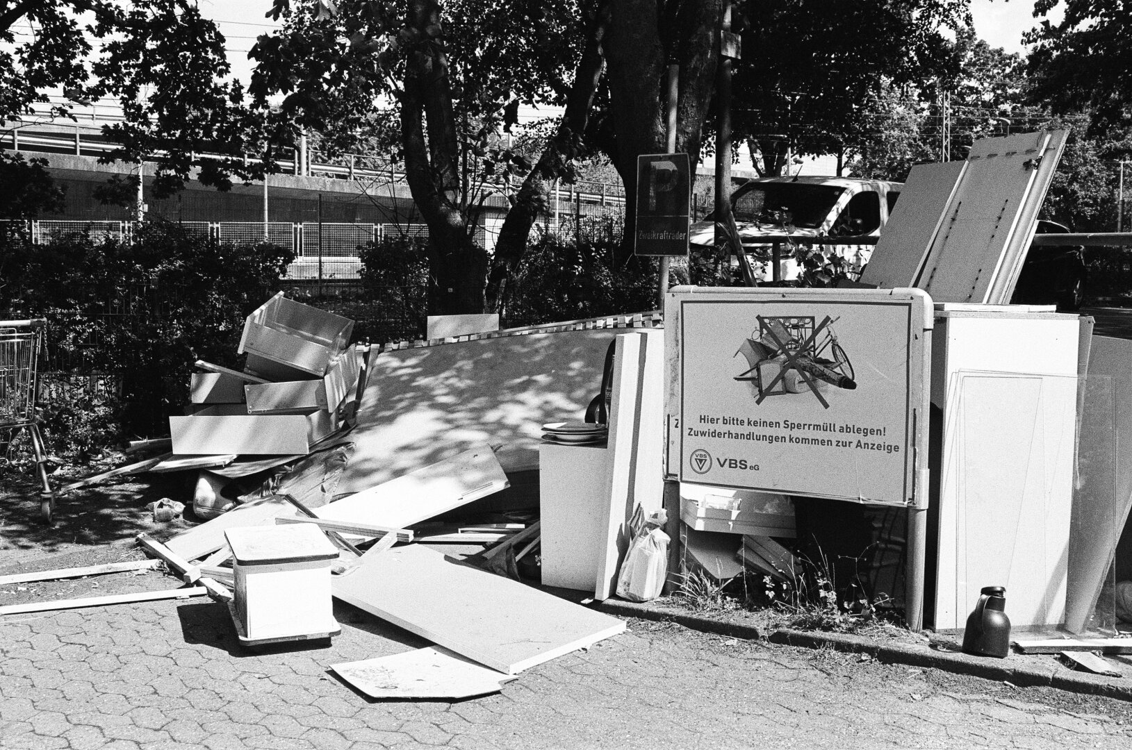 A sign saying „No bulky waste. Violations will be reported.“ Next to the sign: A lot of bulky waste. Rock n Roll!
