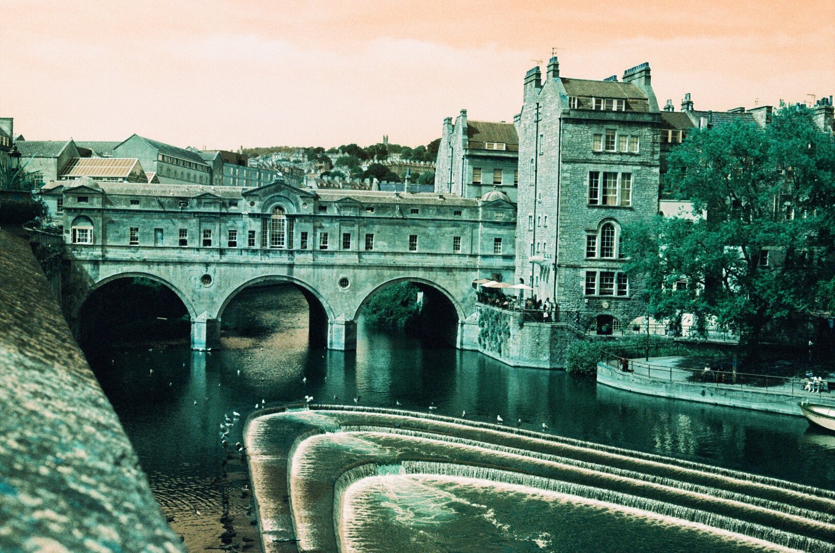 Same shot like before, but completely unedited and with its original colors. As the film used has a turquise touch, the bridge, all the buildings in the back and the water appears in different green tones, the sky is orange.