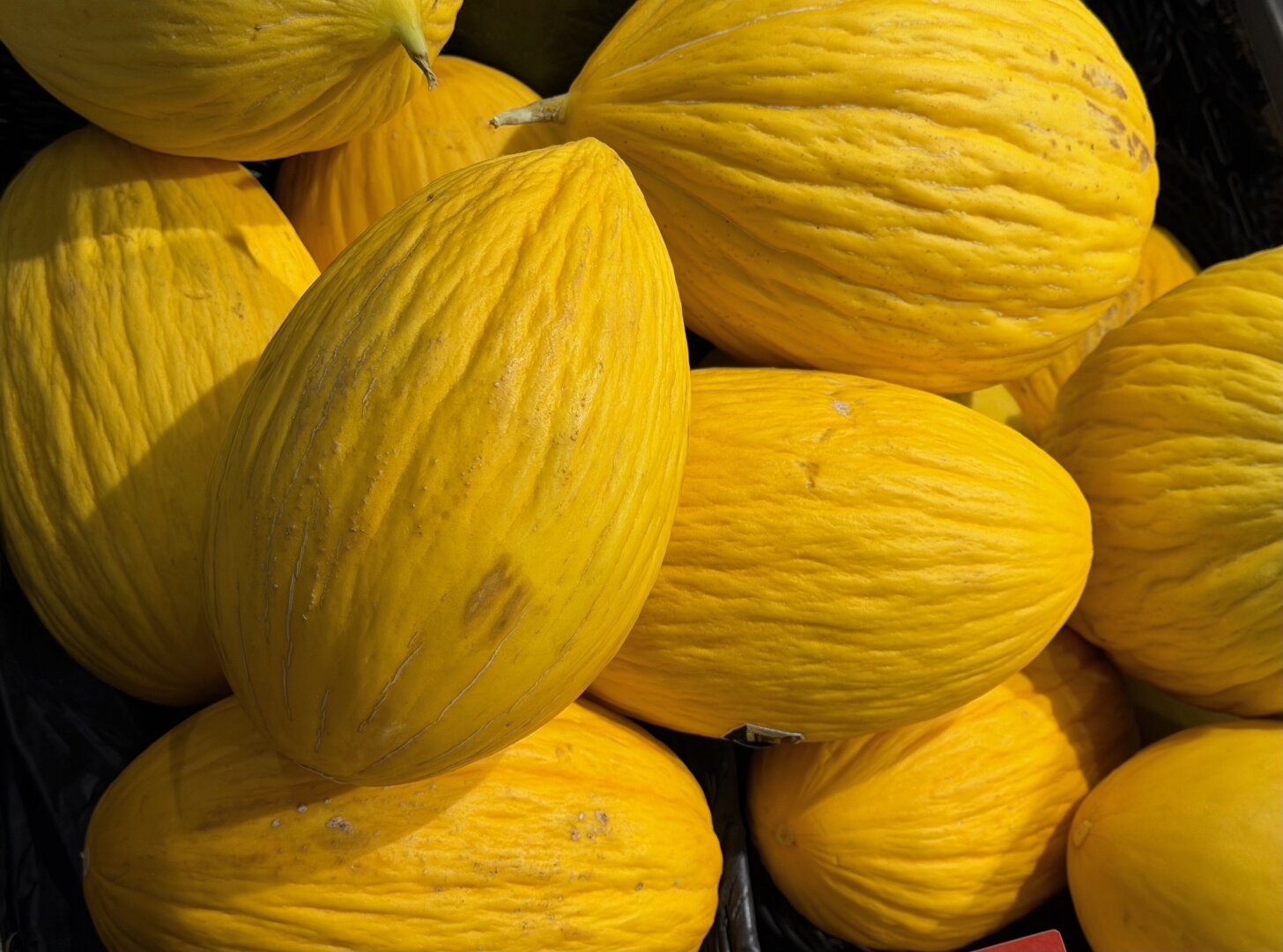 Detail einer Obstkiste mit gelben Honigmelonen.

Detail of a fruit crate with yellow honeydew melons.