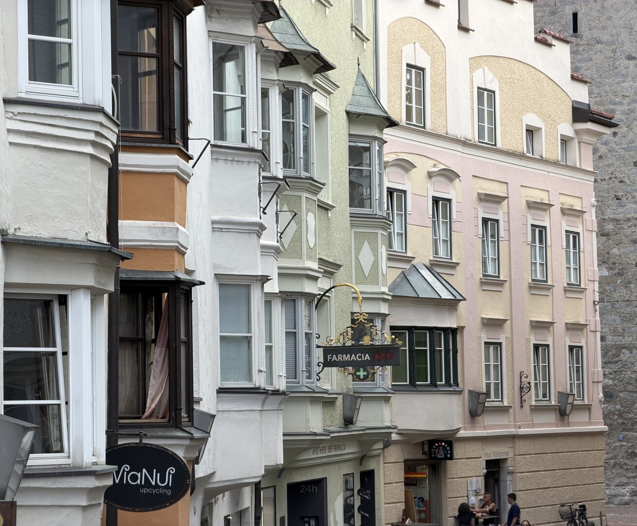 One sees various pastel-colored house facades, richly articulated with window sills and a variety of bay windows.