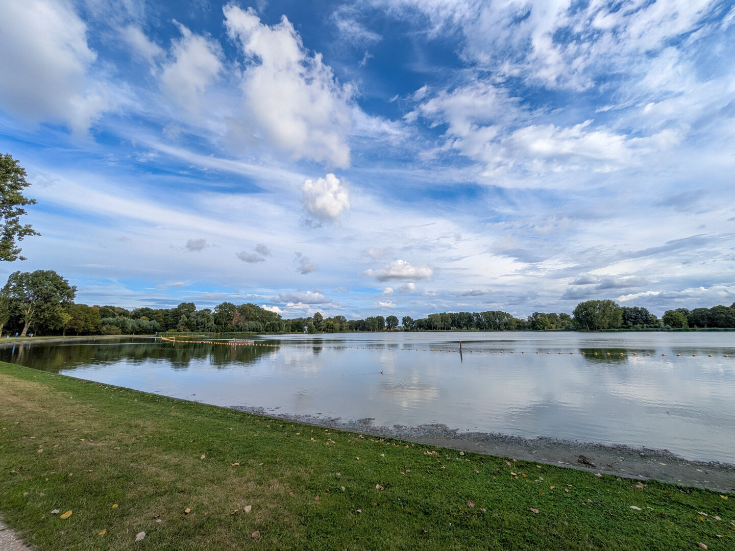 Waterplas met gras ervoor een wolkenlucht