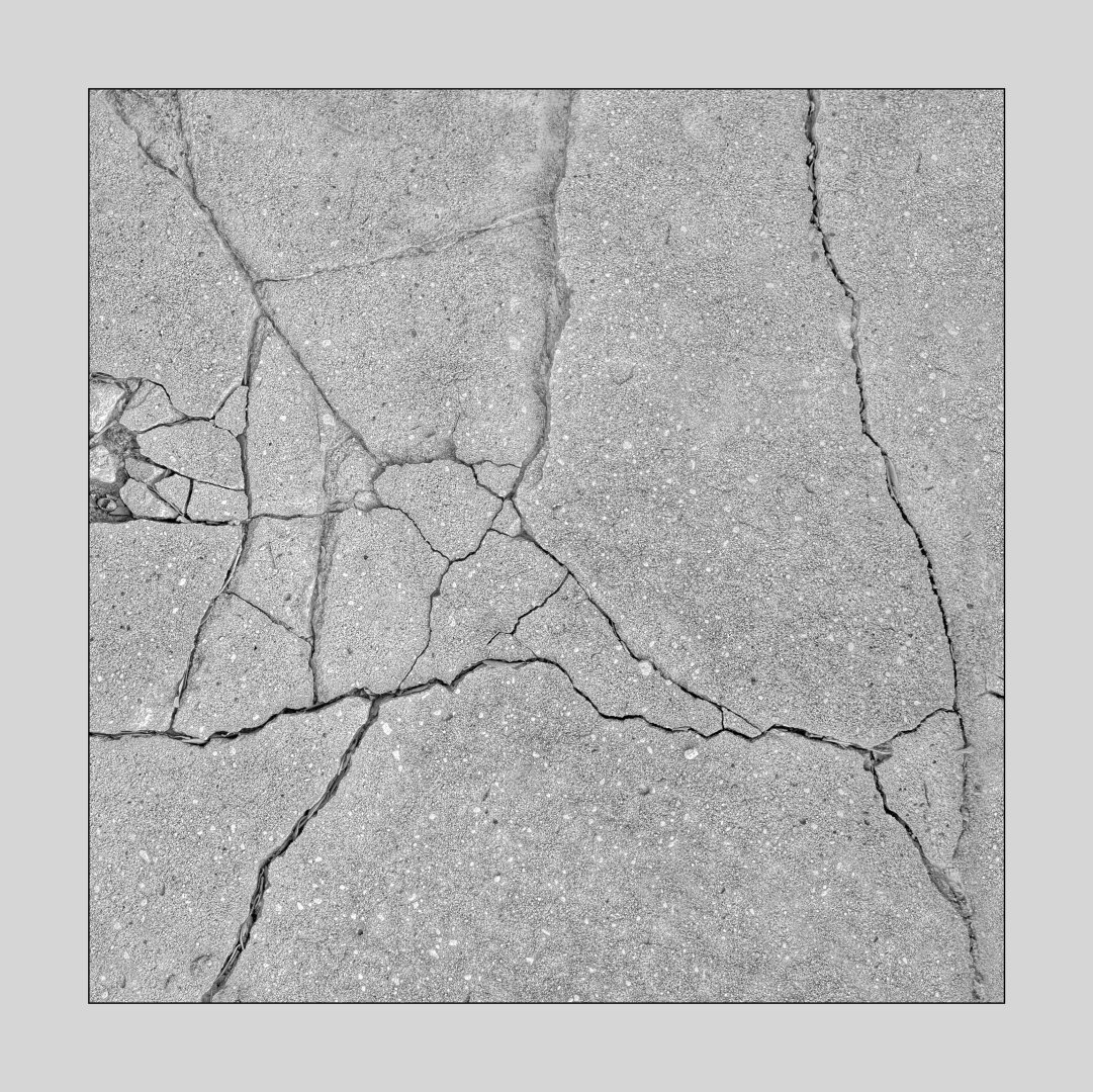 An area of a cement sidewalk with many cracks running over it forming a pleasing abstract composition. All grays, though it is a color photograph. The image has been manipulated for presentation and is not just a snapshot. I crop and clone out distractions and balance tones as I see fit. Square image with an off-white mat around it.