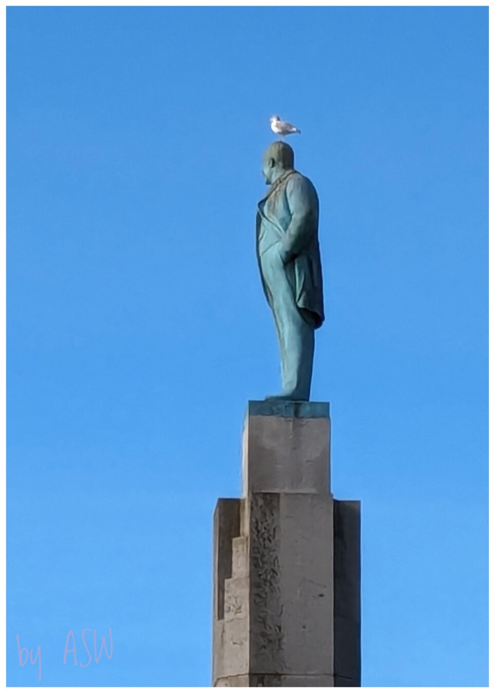 Blauer Himmel eine männliche Statue auf einer Säule mit einer Möve auf dem Kopf / Blue sky, a male statue on a column with a seagull on its head.