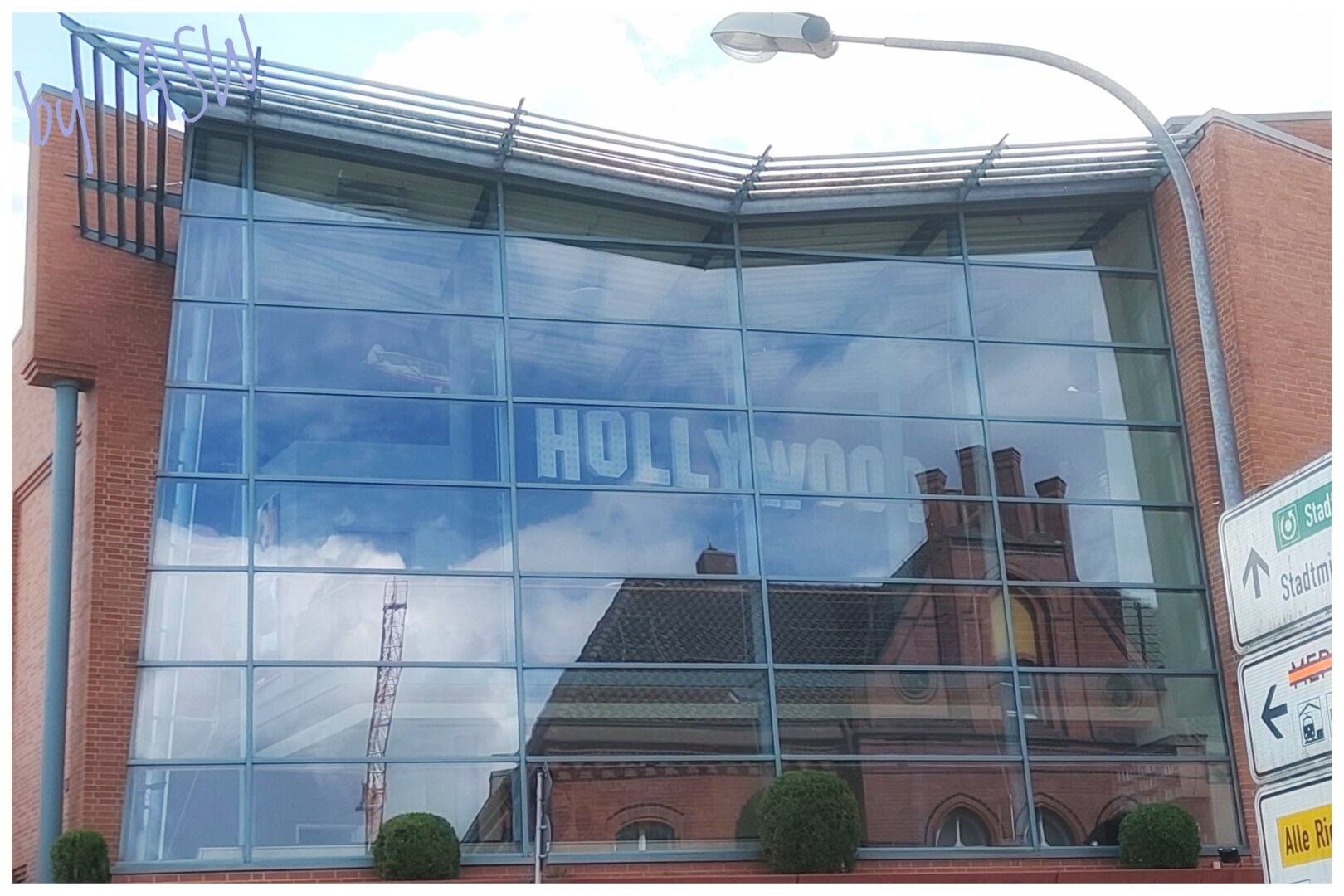 Ein großes Fenster in dem Eine Spiegelung eines Gebäudes mit dem Hollywood Schriftzug zu sehen ist / A large window showing a reflection of a building with the Hollywood sign