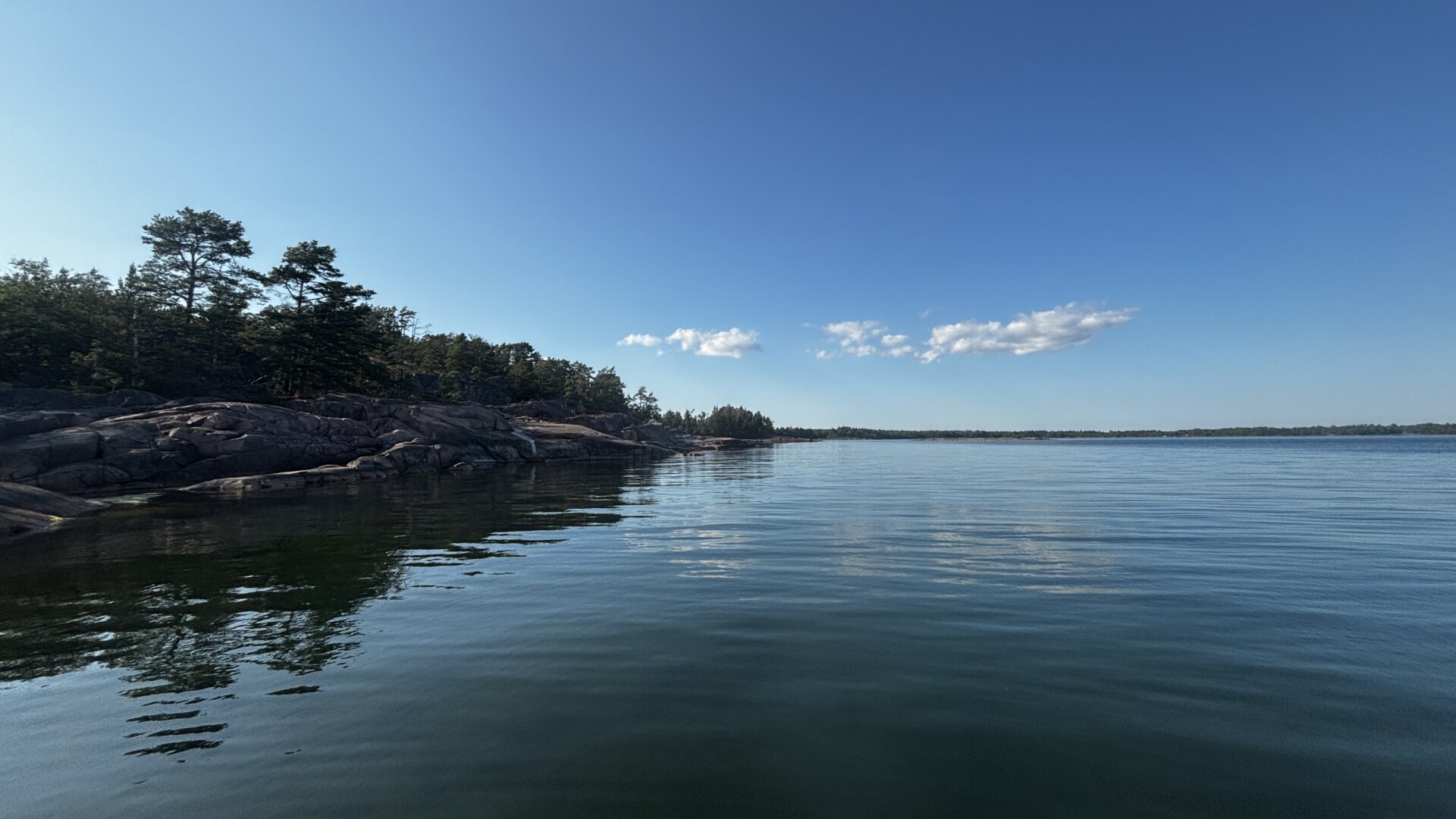 Photo from the water of a cliffy island, calm waters, and blue skies.