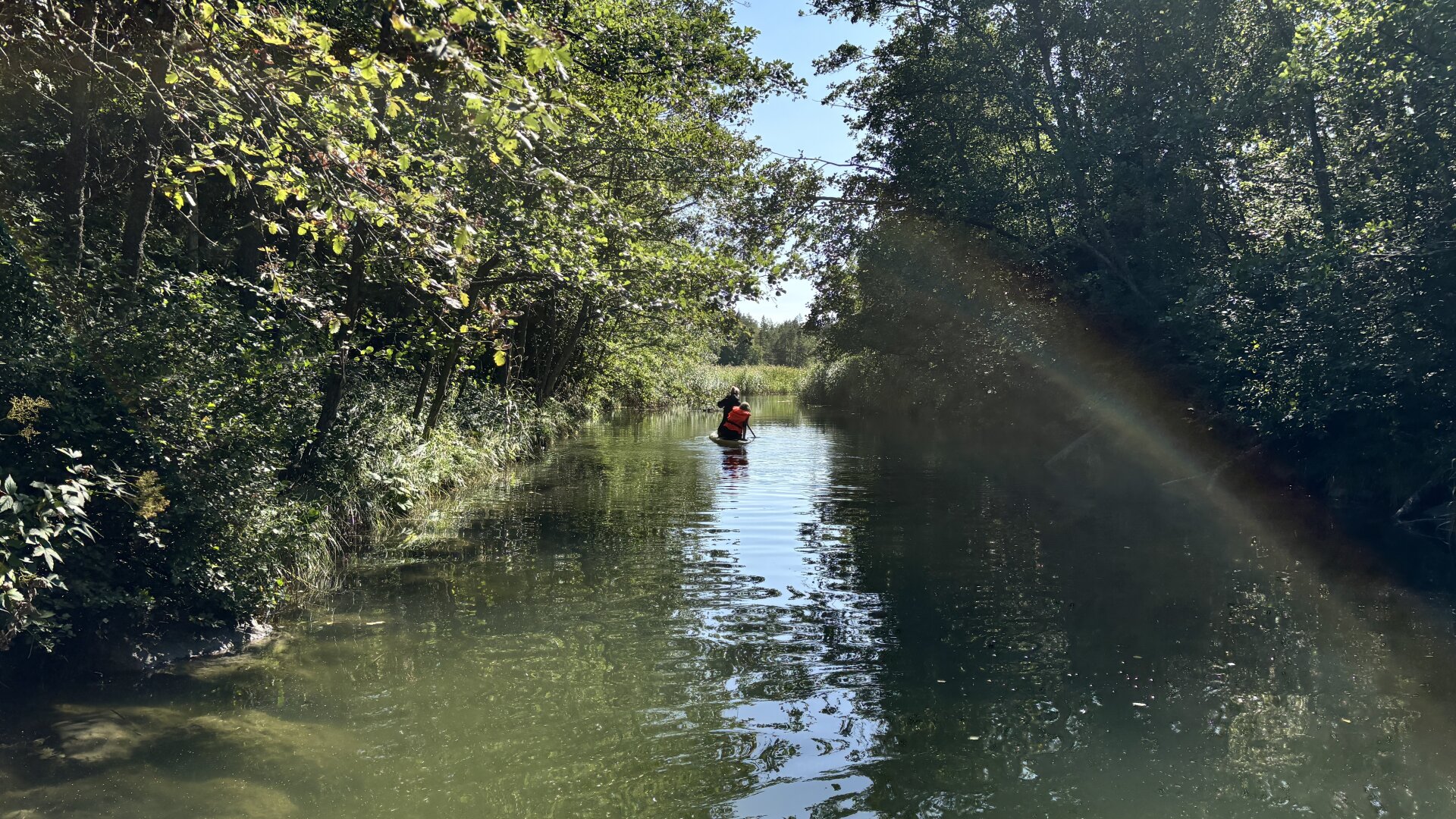 Photo from a tiny overgrown channel with a couple of paddleboards calmly heading through.