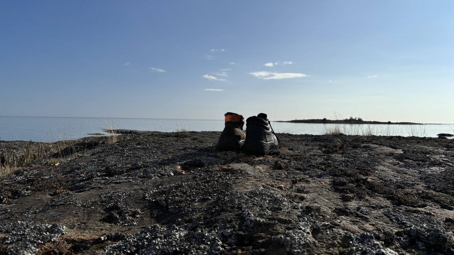 Photo of a pair of boots on a cliff with a view out over the water.