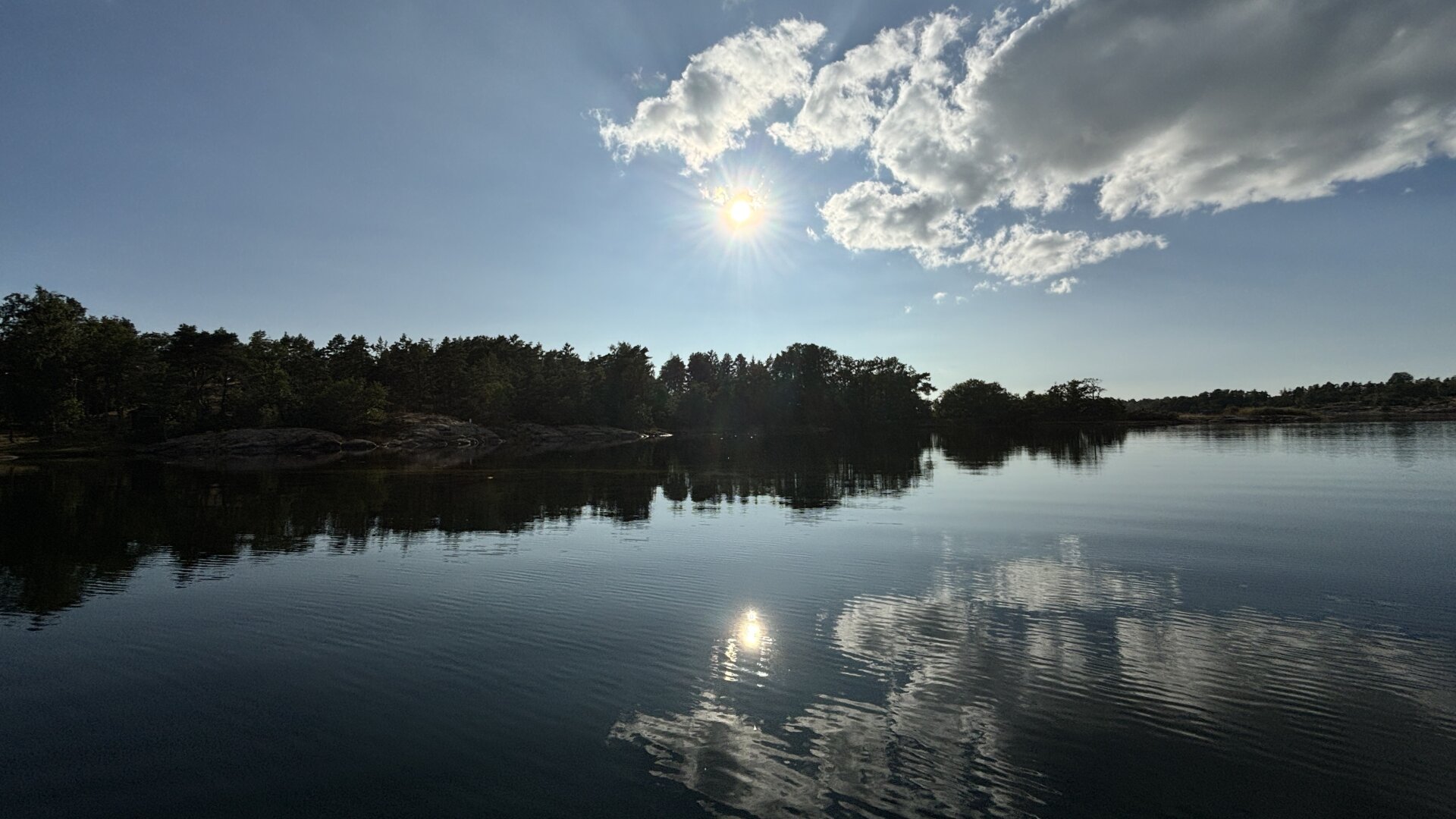 Photo of water and some cliffs with the clouds refelcting in the pretty much beclamed water.